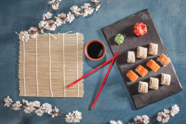 suşi yemek çubukları, zencefil, soya, wasabi ve sakura plaka üzerinde