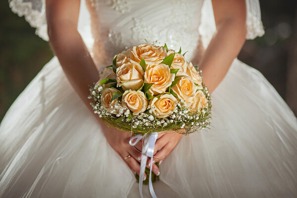 Orange roses in hands of the bride