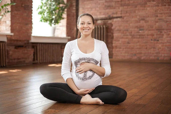 Mujer embarazada haciendo yoga en el interior — Foto de Stock