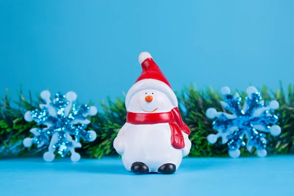 Mavi arka planda Noel süslemeleri olan kardan adam bebeği