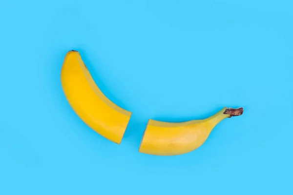 淡蓝色背景的新鲜香蕉切成两半 — 图库照片