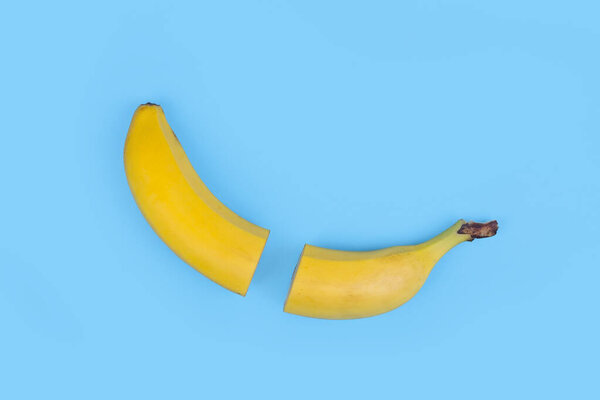 Fresh banana cut in half on light blue background.