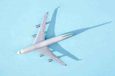 Parlak mavi arka planda gölgesi olan oyuncak uçak