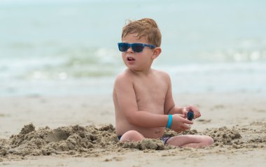 sağlam çocuk çocuk sahilde mavi güneş gözlüğü ile 