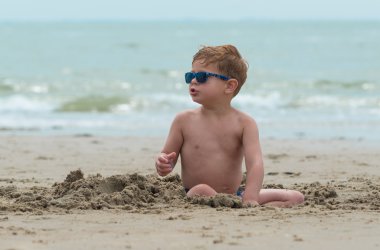 sağlam çocuk çocuk sahilde mavi güneş gözlüğü ile 