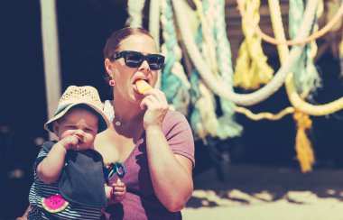 annesiyle şapkasını ile aan dondurma yeme sahilde oturan küçük bebek kız