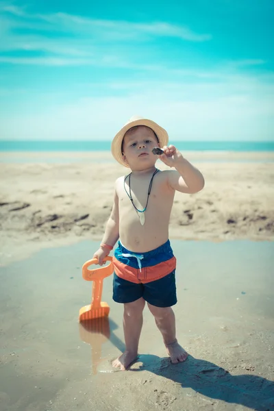 Elbűvölt gyerek nézi a shell, a strandon — Stock Fotó
