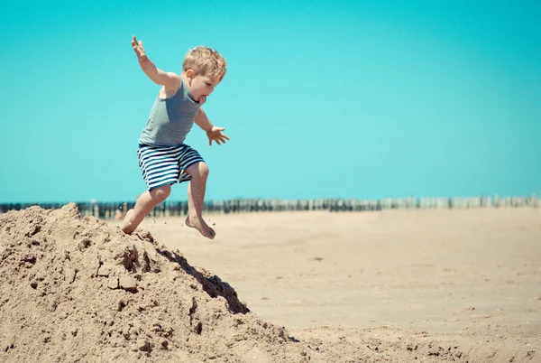 Petit garçon saute d'une montagne sur la plage — Photo