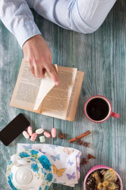 Bir kitap okuma ve ahşap masa üzerinde notlar yazma adam