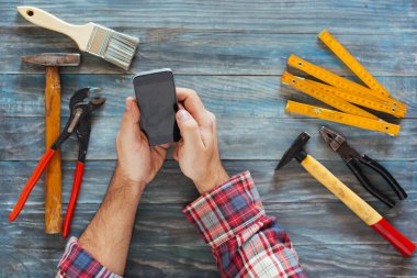 Telefon, talaş ve c ile bir DIY proje üzerinde adam