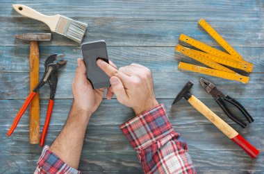 Telefon, talaş ve c ile bir DIY proje üzerinde adam