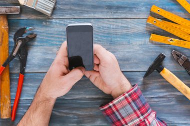 Telefon, talaş ve c ile bir DIY proje üzerinde adam