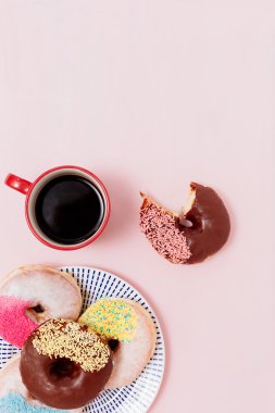 Kahve ve donut pembe bir arka plan üzerinde