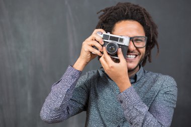 Rustik backgorund oyuncak kamera ile gülümseyen mutlu hipster adam