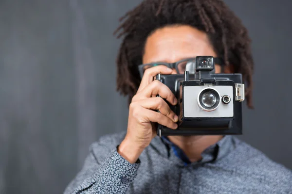 Gelukkig hipster man die lacht met speelgoed camera op rustieke backgorund — Stockfoto