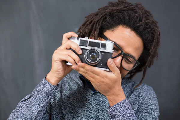 Gelukkig hipster man die lacht met speelgoed camera op rustieke backgorund — Stockfoto