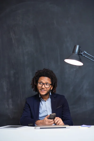 Portrait d'un homme souriant avec un téléphone portable assis au café à l'aide d'un ordinateur portable — Photo