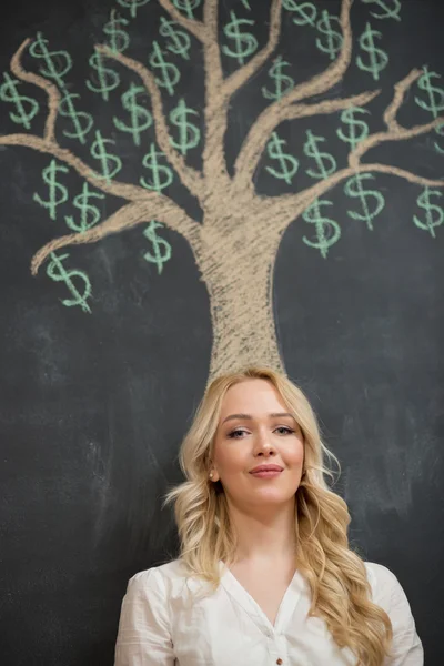 Mujer de negocios rubia feliz delante de tiza árbol de dinero dibujo — Foto de Stock