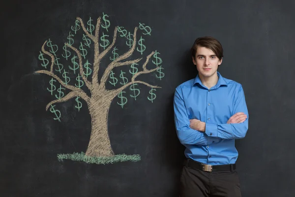 Photo of young businessman on chalkboard background. Dollar tree — Stock Photo, Image