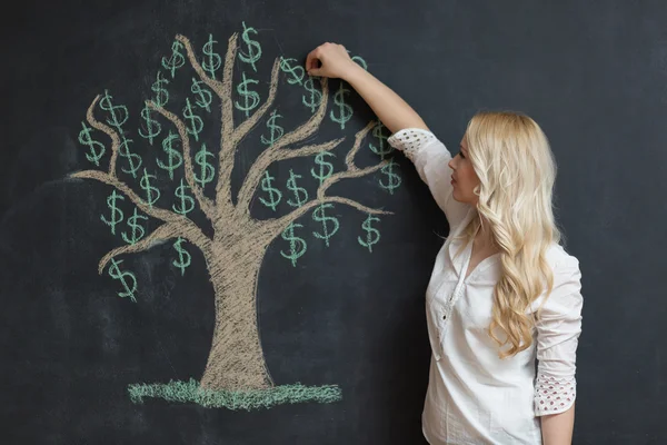 Mujer de negocios rubia feliz delante de tiza árbol de dinero dibujo — Foto de Stock