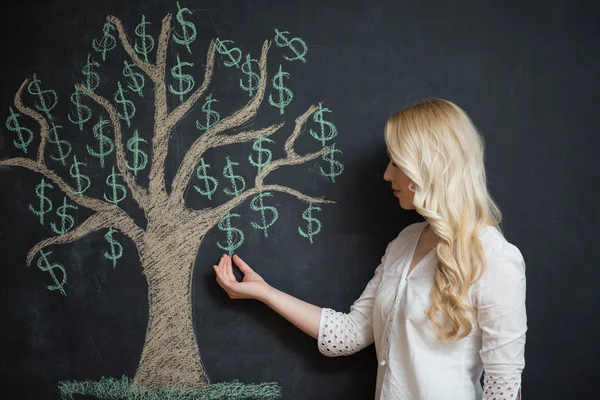 Mujer de negocios rubia feliz delante de tiza árbol de dinero dibujo — Foto de Stock