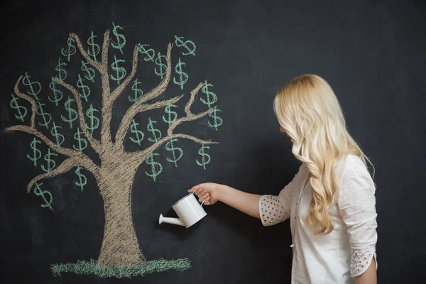 Mujer de negocios rubia feliz delante de tiza árbol de dinero dibujo — Foto de Stock