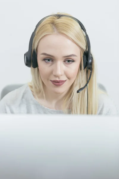 Business woman talking on the phone while working on her computer — стоковое фото