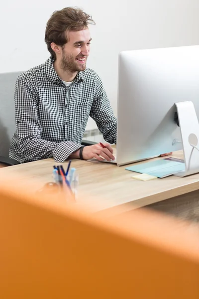 En mann som ser på en dataskjerm og tenker på jobben. – stockfoto