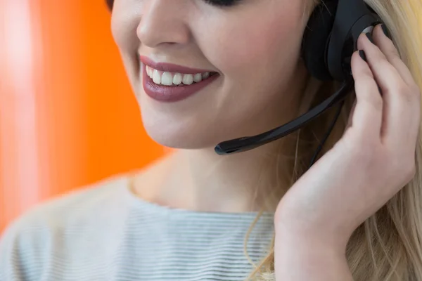 Sorrindo jovem empresária vestindo um fone de ouvido atender chamadas um — Fotografia de Stock