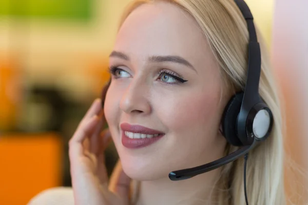 Sorrindo jovem empresária vestindo um fone de ouvido atender chamadas um — Fotografia de Stock