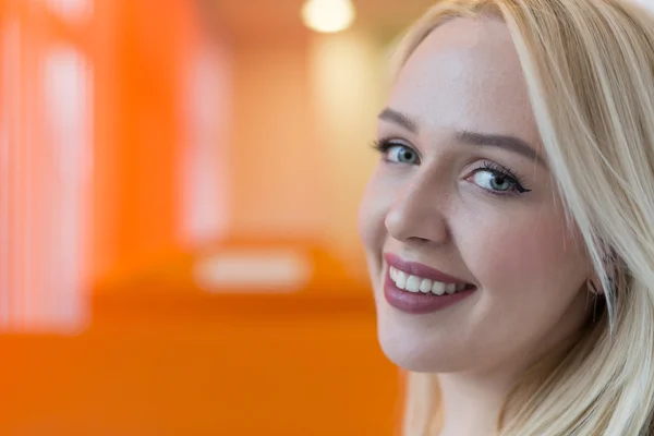 Joven mujer de negocios sonriente con auriculares respondiendo llamadas en un centro de atención al cliente o queriendo comunicarse con las manos libres mientras continúa trabajando en su oficina —  Fotos de Stock