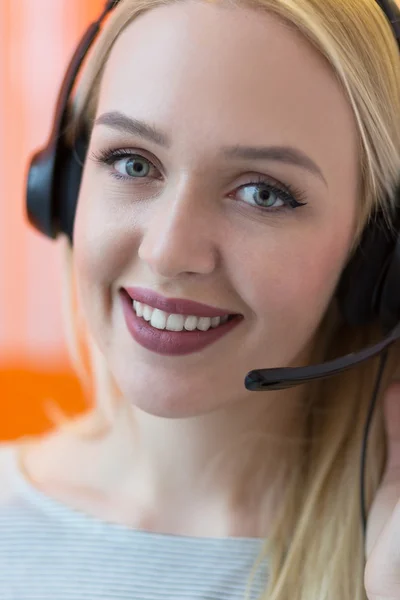 Smiling young business woman wearing a headset answering calls a — Stock Photo, Image