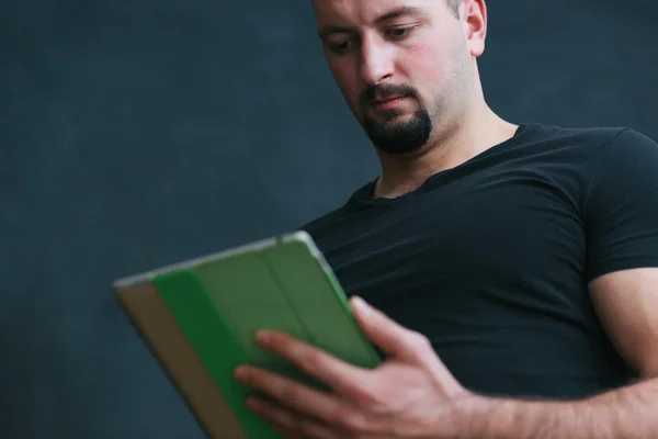 Portret van een knappe jongeman die houden van een tablet in zijn handen — Stockfoto