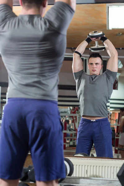 Homem musculoso treinando seus ombros com halteres — Fotografia de Stock