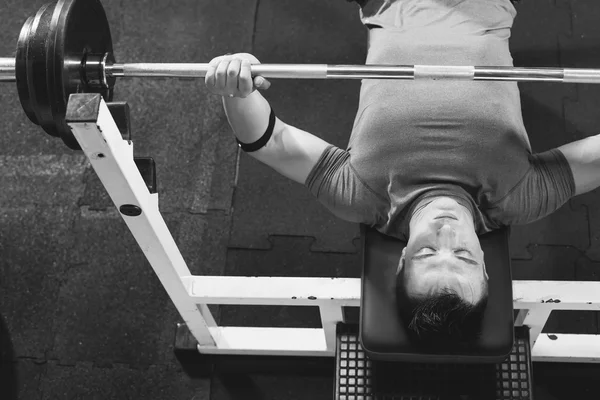 Joven en el gimnasio ejercitando el pecho en la prensa de banca - vista superior — Foto de Stock