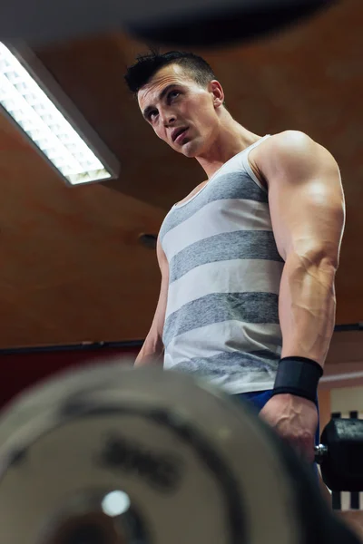 Knappe macht atletische man in opleiding oppompen van spieren met — Stockfoto