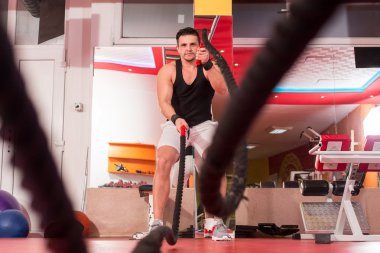 Genç adam birlikte savaş ipler bir spor salonunda egzersiz