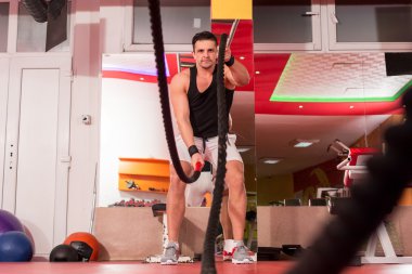 Genç adam birlikte savaş ipler bir spor salonunda egzersiz