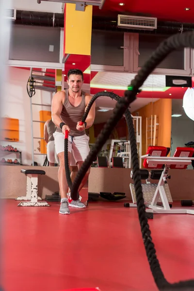 Junger Mann trainiert mit Seilen in einem Fitnessstudio — Stockfoto
