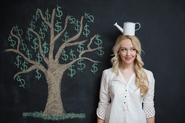 Mujer de negocios rubia feliz delante de tiza árbol de dinero dibujo — Foto de Stock