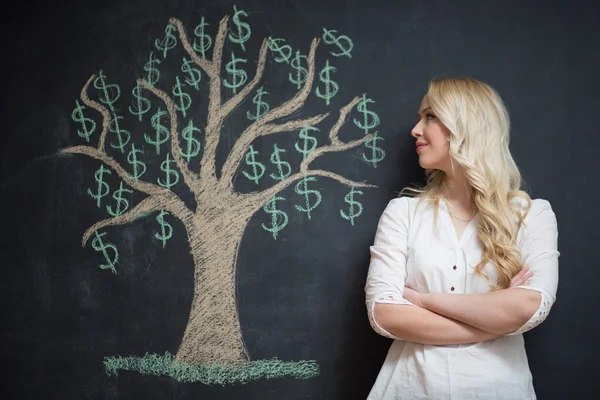 Mujer de negocios rubia feliz delante de tiza árbol de dinero dibujo — Foto de Stock