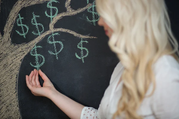 Mujer de negocios rubia feliz delante de tiza árbol de dinero dibujo — Foto de Stock