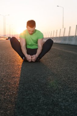 Atletik runner germe egzersiz yaparak sabah için hazırlanıyor
