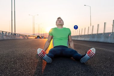 runner siyah asfaltta çalıştırdıktan sonra yalan dinleniyor. M koşu