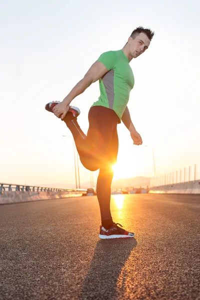 Stretching after jogging on a bridge. — Stock Photo, Image