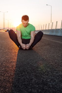 Atletik runner germe egzersiz yaparak sabah için hazırlanıyor