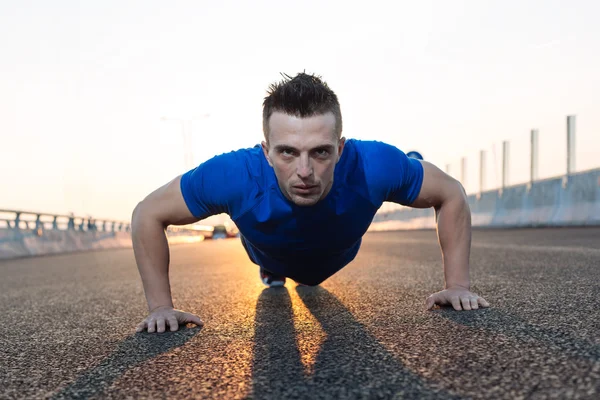 Handsome male runner doing push-ups on stairs in urban setting, — Stock Photo, Image