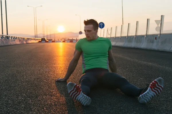 Løberen hviler på en sort asfalt efter løb. Jogging m - Stock-foto