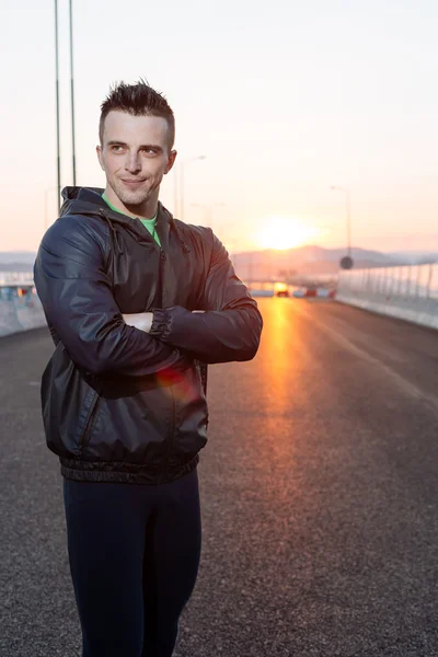 handsome urban jogger rposing on the bridge