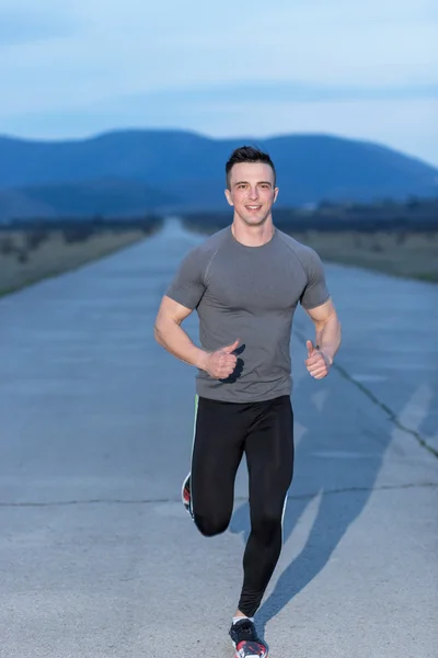 Healthy athlete man jogging at morning on empty roat in the city — Stock Photo, Image